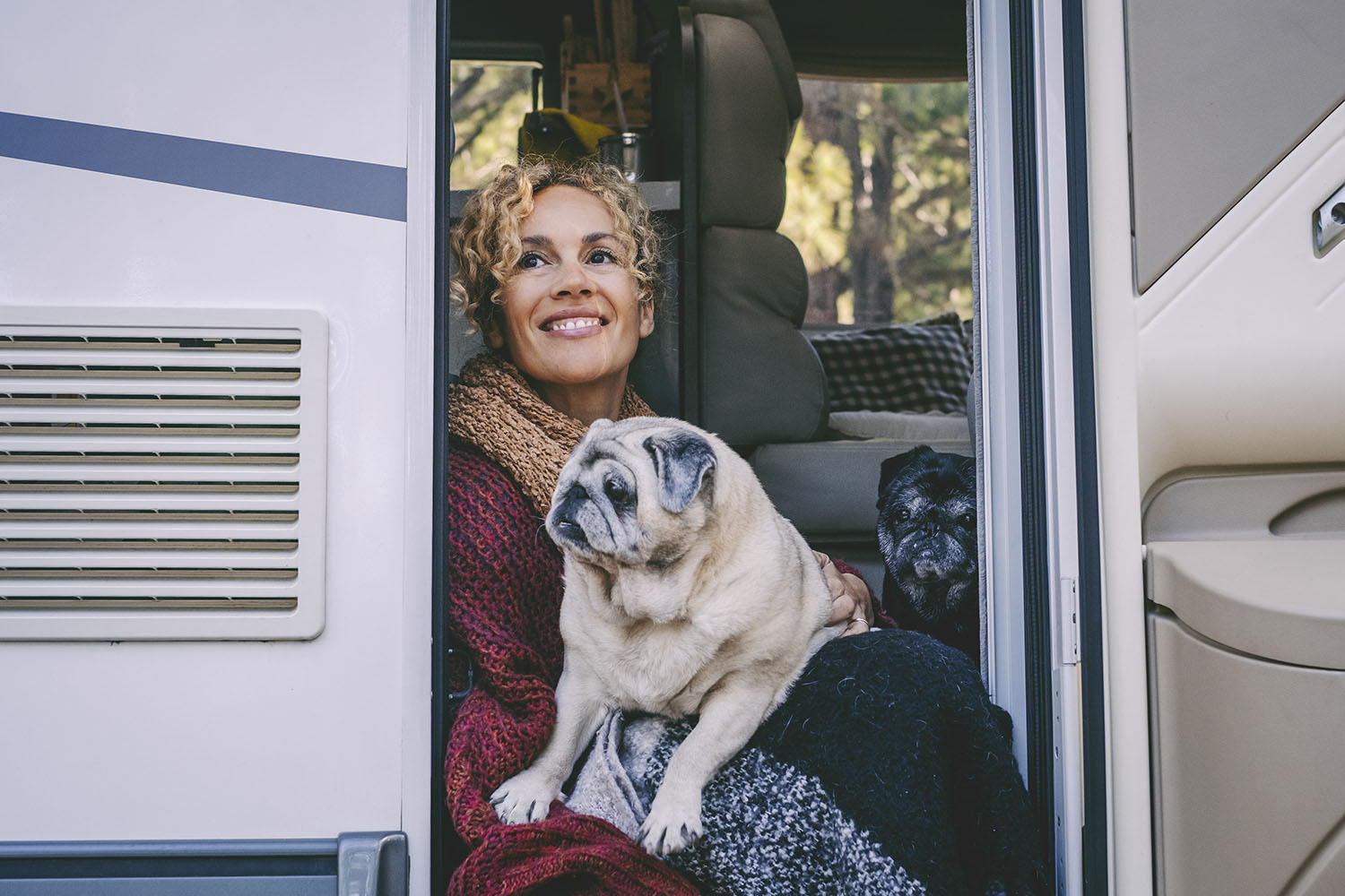 Kobieta z psem siedzi w drzwiach kampera 