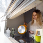 szczęśliwa kobieta myje naczynia w kamperze