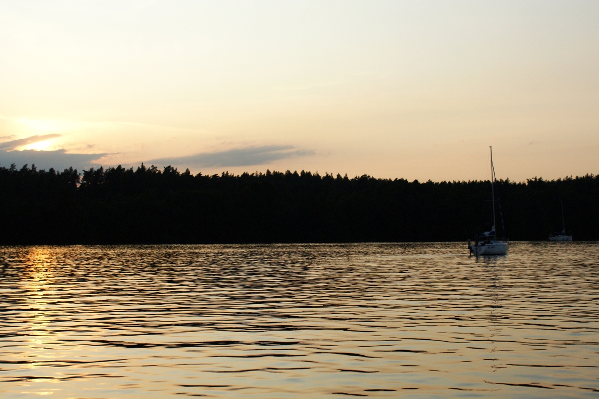 Żaglówka na mazurskim jeziorze o zachodzie słońca